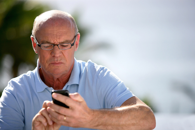 Senior man sending text message